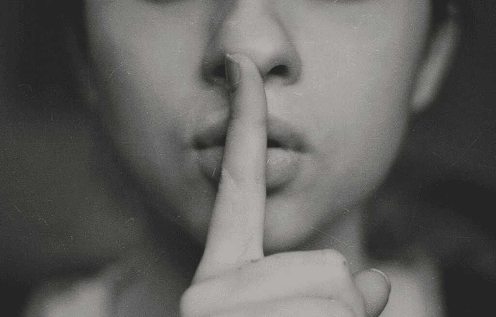Person holding a finger to their lips in a gesture for silence.